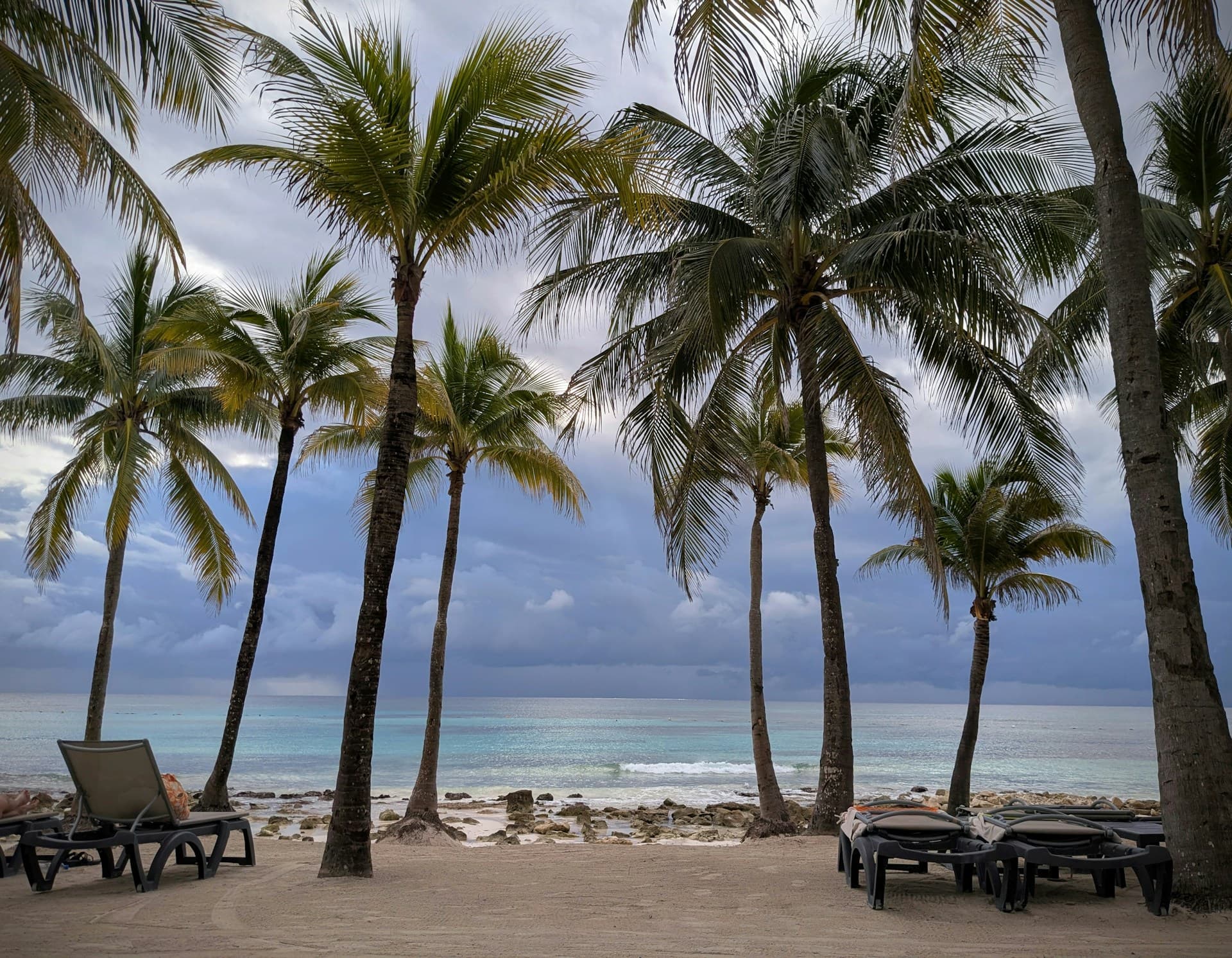 A Riviera Maya beach club with day-beds under palapas and turquoise water beyond