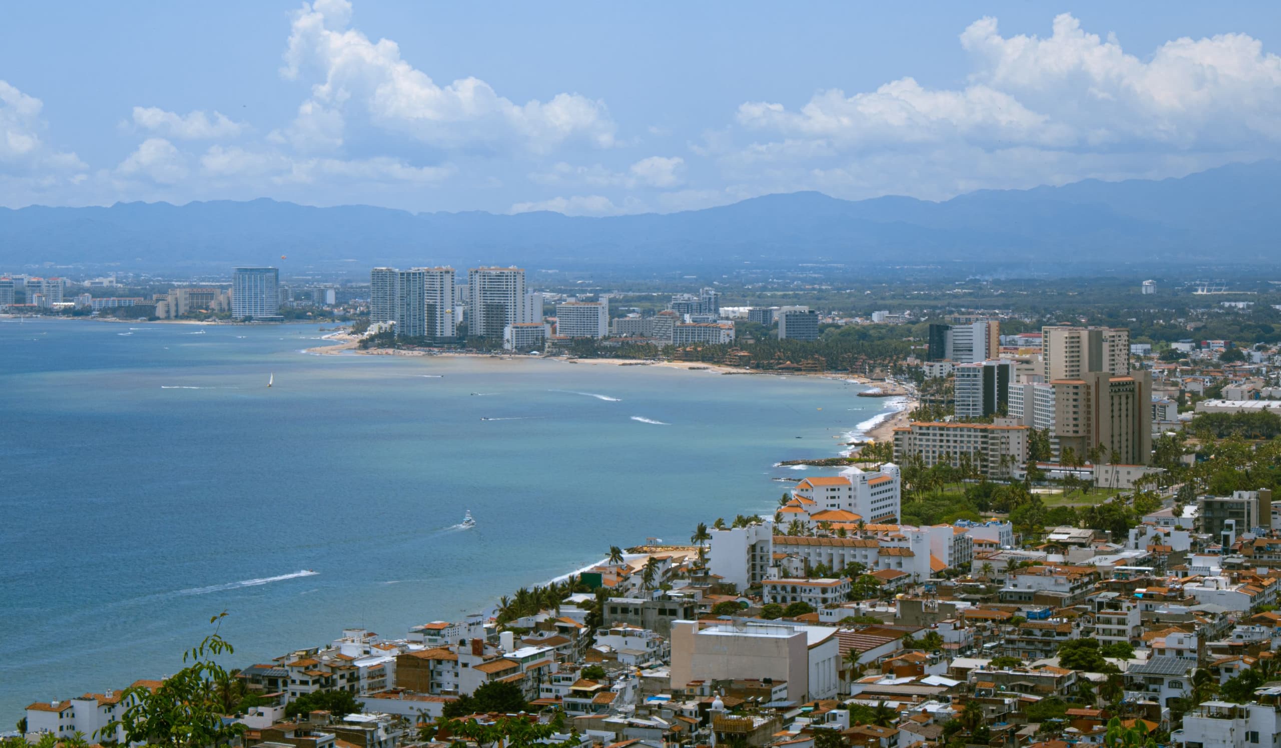 Panoramic aerial view of Puerto Vallarta — beach, skyline, marina, and Sierra Madre mountains